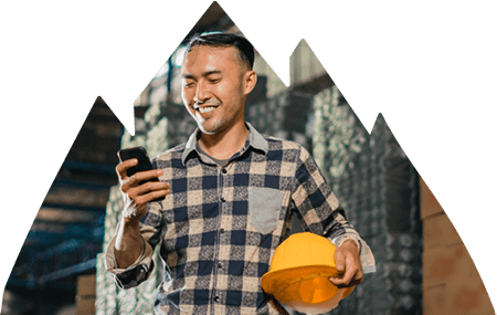 Construction worker holding hard hat in hand and looking at phone in the other. Construction worker holding hard hat in hand and looking at phone in the other.