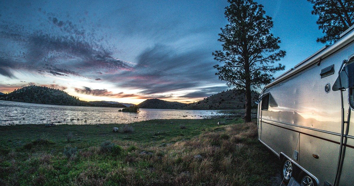 airstream parked on a lake with a beautiful sunset