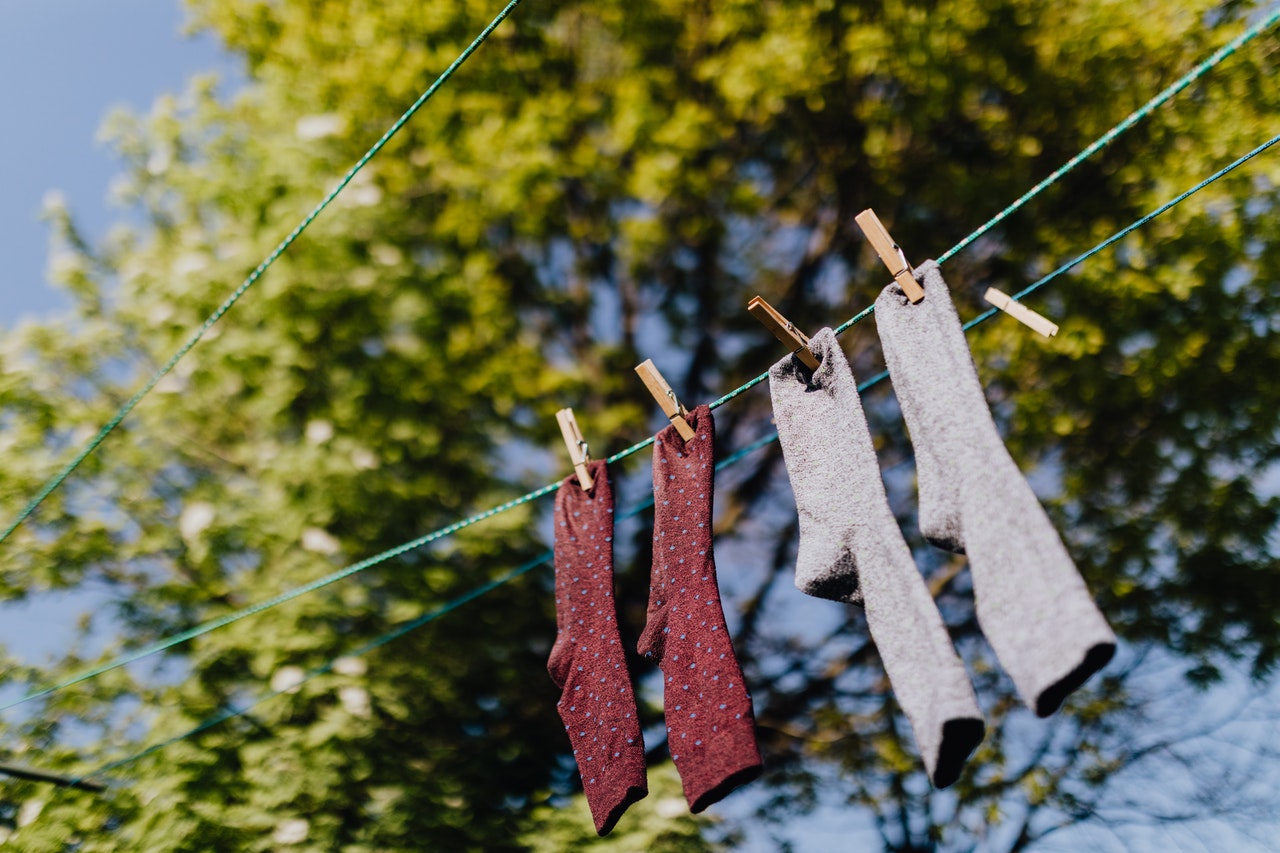 gray and red socks on a clothesline with a tree in the background